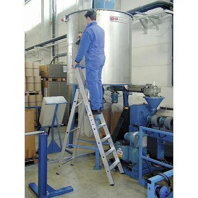 Krause Stehleiter - Arbeitshöhe: 3,4 m, Anzahl Tritte: 6 Stk., Belastbarkeit: 150 kg, Aluminium - Ein Mann in blauer Arbeitskleidung steht auf einer Krause Leiter vor einem großen, silberfarbenen Industrietank.