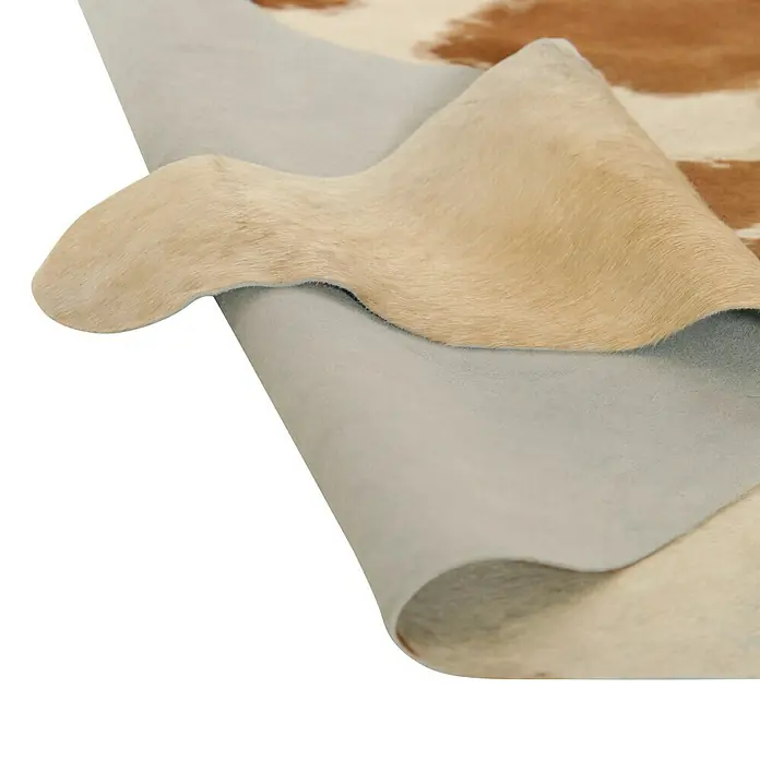 Esbeco Kuhfell - Braun/Weiß, 100 % Echtfell - Detailaufnahme einer Echtfellmatte mit Braun- und Weißtönen, die die Textur und die hochwertige Verarbeitung hervorhebt.