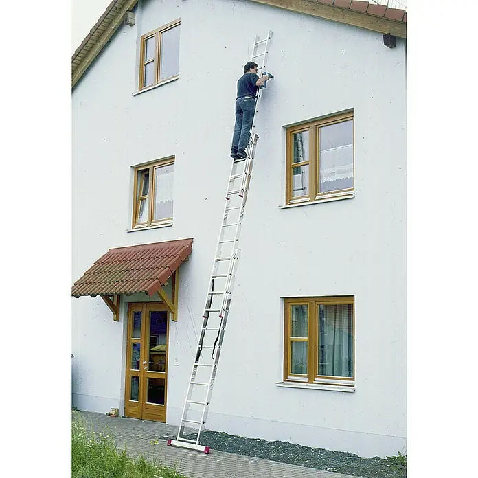 Krause Corda Escalera multiusos - Altura de trabajo: 7,3 m, Número de peldaños: 33 ud., Carga soportada: 150 kg, Aluminio - Un hombre utiliza una escalera larga para trabajar en la pared de la casa. La escalera parece una herramienta robusta y confiable para esta tarea.