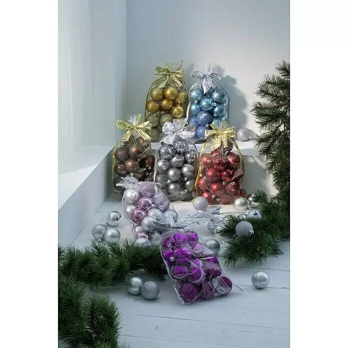 Weihnachtskugeln im Geschenkbeutel - Rot, Kunststoff, Durchmesser: 6 cm, 20 Stk. - Verschiedene farbige Weihnachtsbaumkugeln in transparenten Beuteln mit Schleifen und lose auf hellem Holzgrund, umgeben von Tannenzweigen.