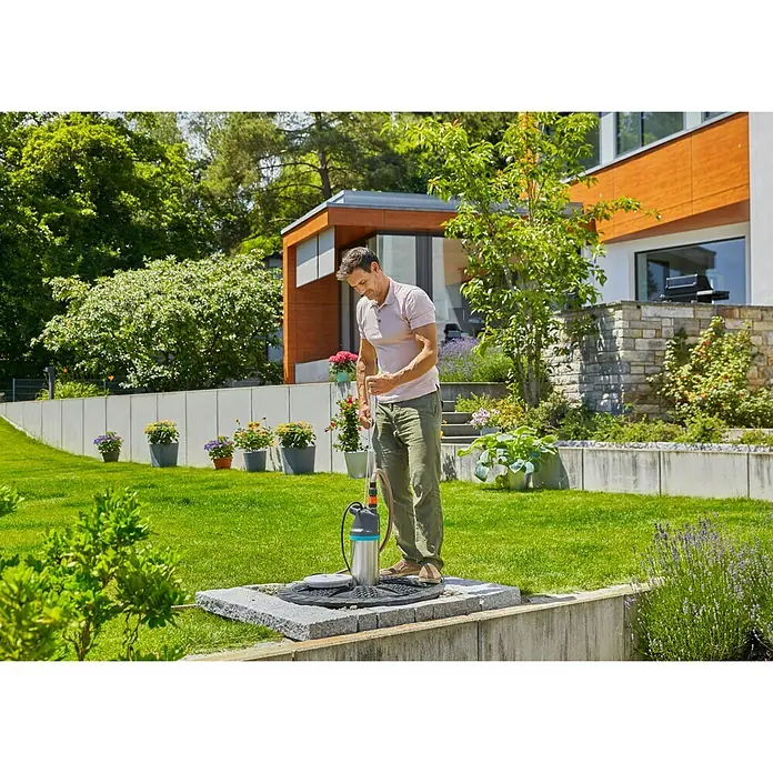 Gardena Drucktauchpumpe 6100/5 inox automatic - 1.100 W, Max. Fördermenge: 6.100 l/h - Ein Mann benutzt eine Gardena Tauchdruckpumpe im Garten, um Wasser abzupumpen. Ideal für Gartenbewässerung und Entwässerung.