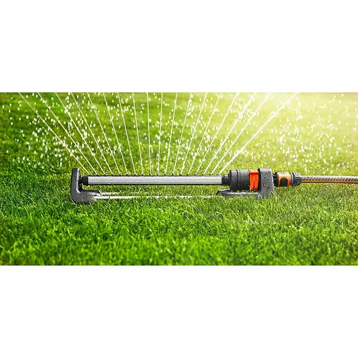 Gardena Viereckregner Aqua L - Max. Regnerfläche: 120 m² - 280 m² - Ein Rasensprenger bewässert einen grünen Rasen. Das Bewässerungssystem ist schwarz, grau und orange und wird im Garten verwendet.