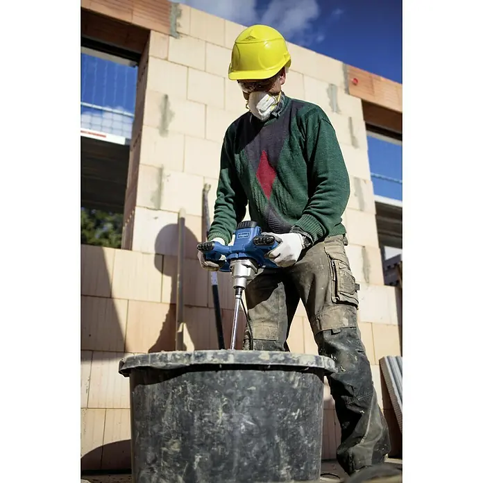 Scheppach Varilla mezcladora de pintura y mortero PM1200 - 1.200 W, Diámetro paleta de mezcla: 120 mm, M 14 - Un trabajador de la construcción usa un mezclador de mortero Scheppach para mezclar mortero en una obra. Equipo de protección presente.