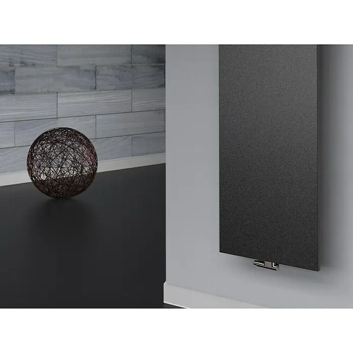 Szagato Designheizkörper Manhattan 3 - B x H: 470 x 1.800 mm, Wärmeleistung bei Vorlauftemperatur von 75 °C (D: 50): 1.118 W, Moonstone-Grau, Mit 2 Handtuchhalter (50 mm) - Ein modernes, dunkles Paneelheizkörper-Design, das an einer Wand montiert ist, neben einem dekorativen Kugelobjekt.