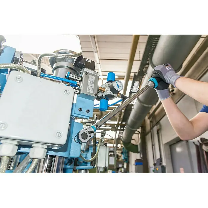 Hazet Drehmomentschlüssel 5123-3CT - ½″ Vierkant, 60 Nm - 320 Nm - Der Hazet Drehmomentschlüssel Serie 7000 eCT mit Feineinstellung wird an einer blauen Maschine verwendet, was die Präzision bei der Montage betont.