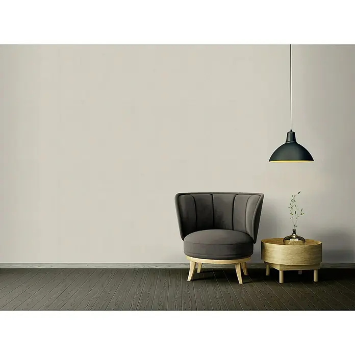 A.S. Création Ethnic Origin Vliestapete I - Dunkelbeige, Uni, 10,05 x 0,53 m - Elegantes Interieur mit einem stilvollen grauen Sessel, einem Beistelltisch mit Blumenvase und einer modernen Hängelampe.