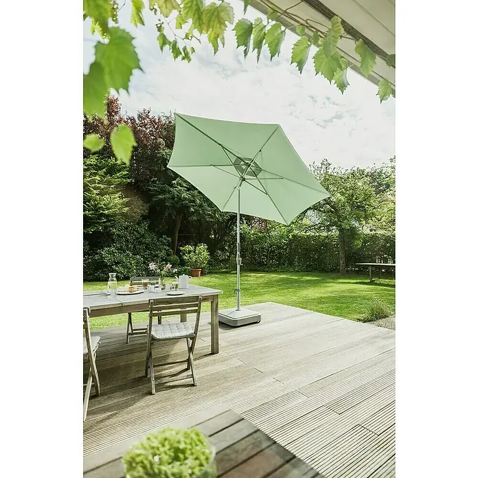 Suncomfort Marktschirm rund SlideFrost-Grün, Durchmesser Bespannung: 300 cm - Gartenszene mit hellgrünem Sonnenschirm neben einem Tisch und Stühlen auf einer Holzterrasse. Ideal für entspannte Stunden im Freien.