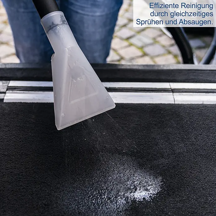 Scheppach Waschsauger SprayVac20 - 1.600 W, 20 l - Detailaufnahme eines Sprühextraktionsgeräts bei der Reinigung eines schwarzen Teppichs, das Reinigungsflüssigkeit versprüht.