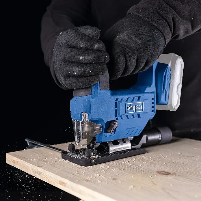 Scheppach IXES 20V Akku-Pendelhubstichsäge C-JS220-X - 20 V, Li-Ionen, Anzahl Akkus: Ohne Akku, Leerlaufhubzahl: 0 /min - 2.400 /min - Nahaufnahme einer Scheppach Akku-Stichsäge beim Sägen eines Holzstücks, bedient von einer Person mit Handschuhen.