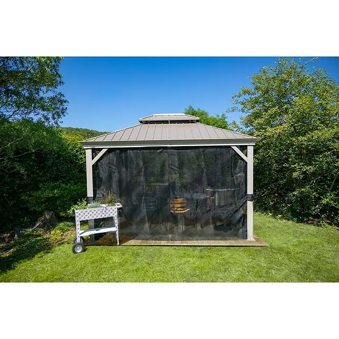 Sojag Standard-Pavillon Messina - B x T: 483 x 363 cm, Farbe Gestell: Champagner, Aluminium - Eine Gartenlaube mit einem schwarzen Netzvorhang und einem Pflanzgefäß auf Rädern. Das Set bietet einen schattigen und stilvollen Platz im Freien.