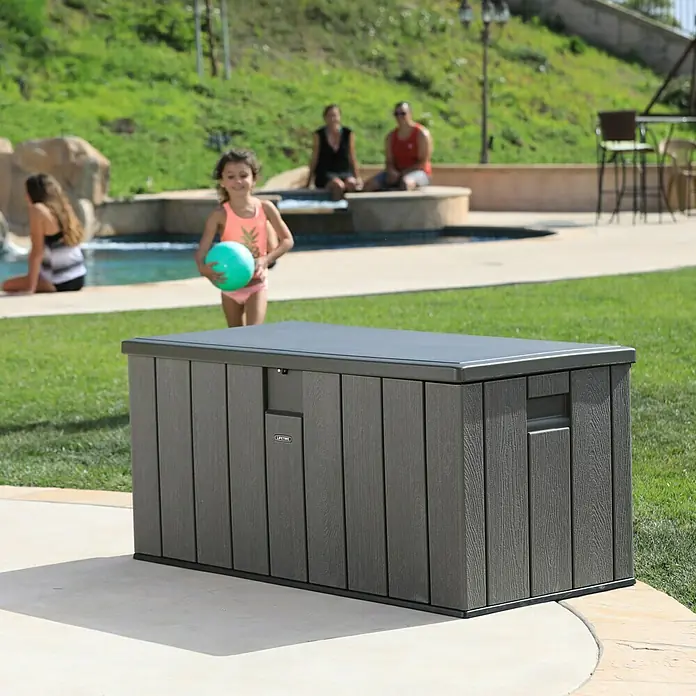 Lifetime Gartenbox - L x B x H: 151 x 72 x 69 cm, Kunststoff, 570 l, Dunkelgrau - Diese Aufnahme zeigt eine Lifetime Aufbewahrungsbox im Freien mit Badegästen im Hintergrund. Eine ideale Lösung für die Poolaufbewahrung.