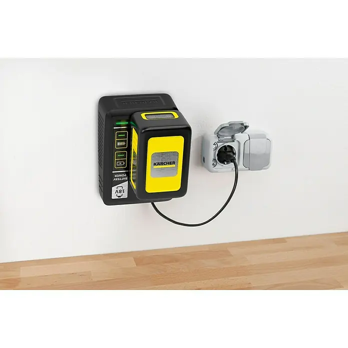 Kärcher Schnellladegerät Battery Power 18 V - Passend für: Kärcher Li-Ionen-Akkus 18 V Battery Power - Eine Nahaufnahme eines Kärcher-Akkuladegeräts mit eingesetztem Akku, an einer Wand befestigt und an eine Steckdose angeschlossen.