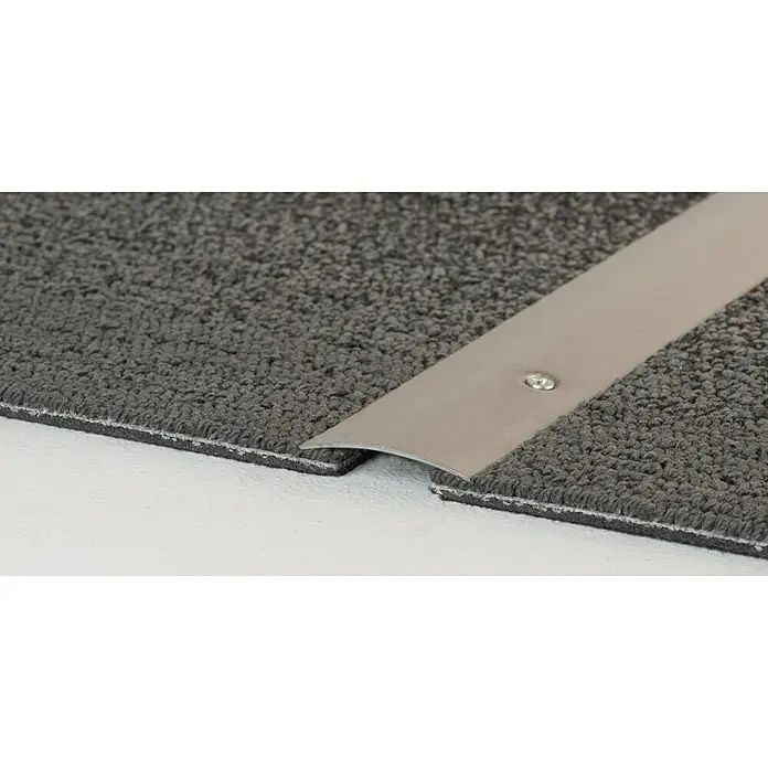 LOGOCLIC Übergangsprofil 113 - Edelstahl gebürstet, 0,9 m x 40 mm x 4,2 mm, Montageart: Schrauben, Seitlich versenkt gelocht - Nahaufnahme einer Übergangsschiene aus Metall, die zwei Teppichböden unterschiedlicher Höhe verbindet. Die Schiene ist mit einer Schraube befestigt.