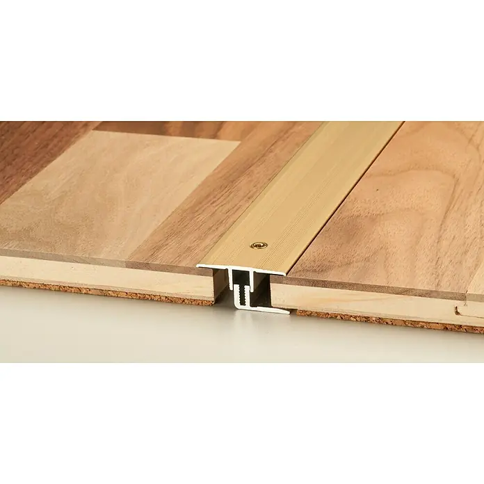 LOGOCLIC Übergangsprofil 220 - Gold, 0,9 m x 34 mm, Montageart: Schrauben - Detailaufnahme einer Übergangsschiene aus Metall zwischen zwei Holzböden, die für einen nahtlosen Übergang sorgt.