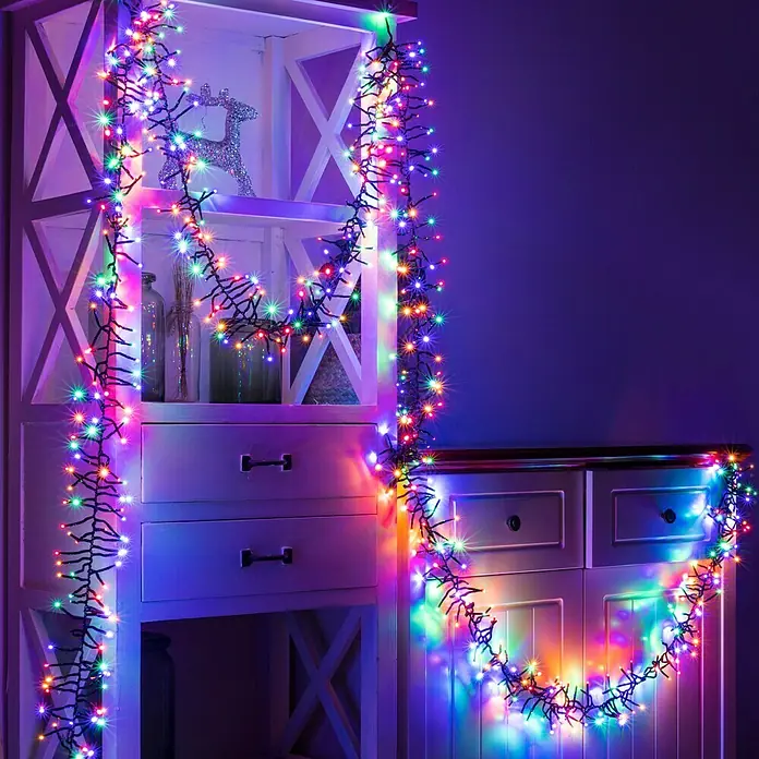 Tween Light Cadena de luces LED - Para exterior, Largo: 8,15 m, 768 ud. - Iluminación festiva: Luces de colores adornan una estantería y una cómoda, ideales para Navidad u otras ocasiones festivas.