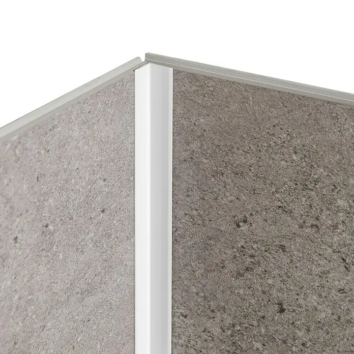Grosfillex Wall+ Winkelleiste innen - 2.600 x 12 x 12 mm, Weiß - Nahaufnahme einer Ecke mit einem weißen Eckprofil, das zwei graue Oberflächen verbindet und einen sauberen Abschluss bildet.