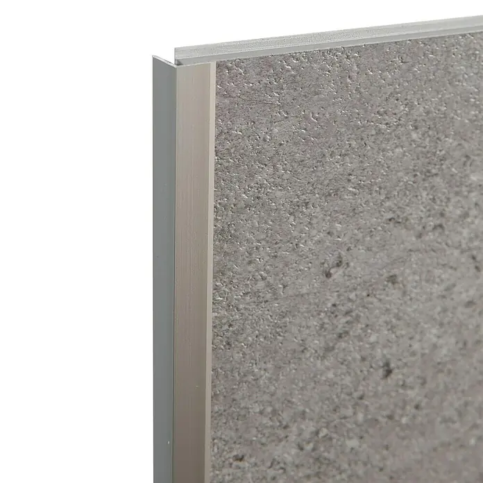 Grosfillex Wall+ Winkelleiste außen - 2.600 x 12 x 12 mm, Titan - Nahaufnahme einer grauen Wandfliese mit einer silbernen Kantenschutzleiste, die das moderne Design hervorhebt.