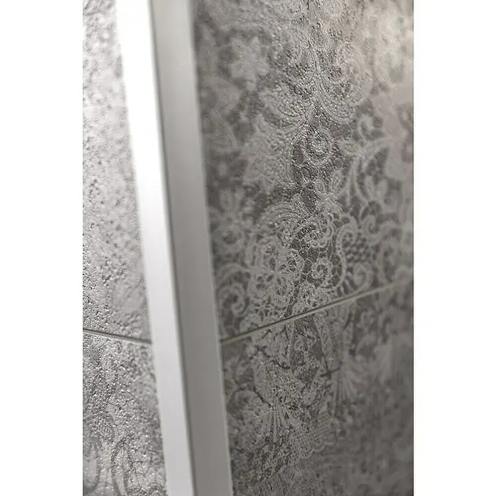 Grosfillex Wall+ Wandpaneel - Cement Flow, 900 x 450 x 5 mm - Nahaufnahme einer grauen Wandfliese mit einem filigranen, weißen Spitzenmuster und einem weißen Rahmen. Die Textur ist leicht rau.