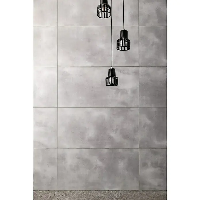 Grosfillex Wall+ Wandpaneel - Grey Cement, 900 x 450 x 5 mm - Das Bild zeigt eine Wandfliese in Betonoptik, die mit drei dekorativen Hängeleuchten kombiniert wurde, um ein modernes Ambiente zu schaffen.