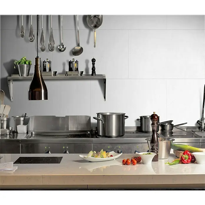 Grosfillex Wall+ Wandpaneel - White Stone, 900 x 450 x 5 mm - Profiküche mit Edelstahlgeräten, Arbeitsfläche mit frischen Zutaten und hängenden Küchenutensilien.