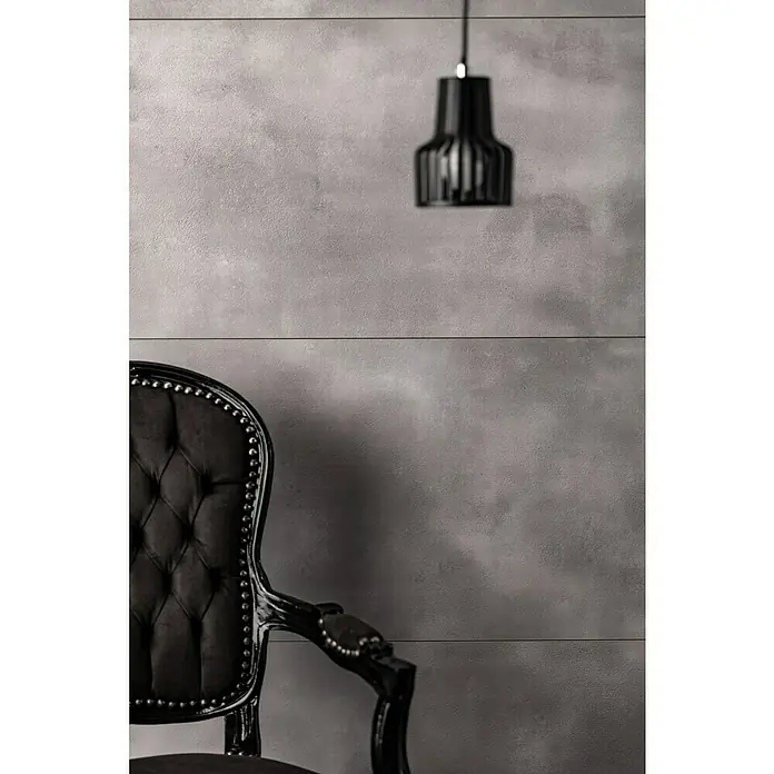 Grosfillex Wall+ Wandpaneel - Grey Cement, 900 x 450 x 5 mm - Elegantes Interieur mit einem schwarzen Sessel mit Knopfleiste und einer stilvollen Pendelleuchte, die dem Raum eine edle Note verleiht.