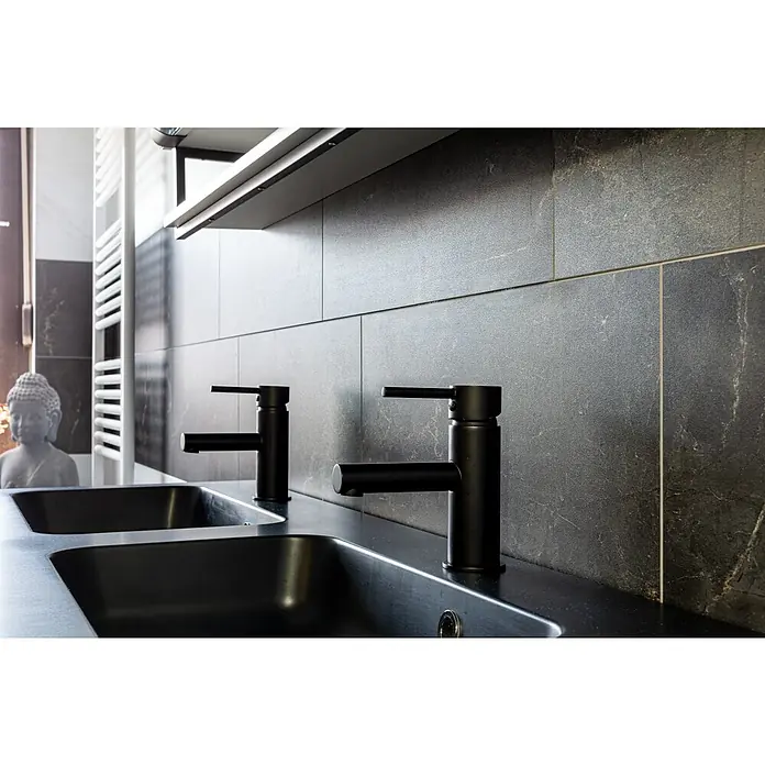 Grosfillex Wall+ Wandpaneel - Black Marble, 600 x 300 x 5 mm - Nahaufnahme eines Badezimmers mit zwei schwarzen Waschbeckenarmaturen vor einer gefliesten Wand. Eleganz und modernes Design vereinen sich.