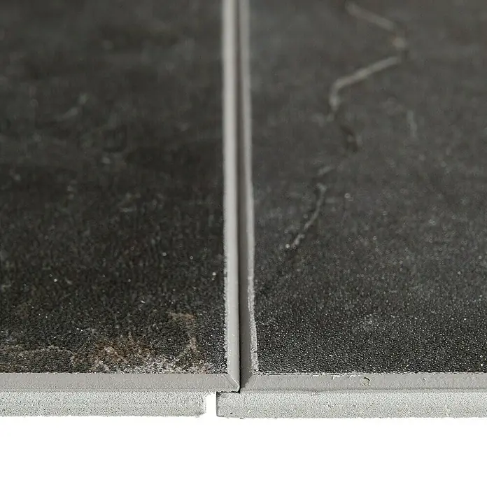 Grosfillex Wall+ Wandpaneel - Black Marble, 600 x 300 x 5 mm - Nahaufnahme von zwei dunklen Bodenfliesen, die durch eine graue Fuge getrennt sind, mit sichtbarer Textur und Kanten.