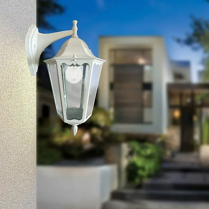 Panaled Vagg Aplique exterior - 60 W, 28,3 x 22,4 x 42 cm, Blanco, IP44, Descendente - Primer plano de una farola de pared blanca para exteriores fijada a una pared, que emite un brillo cálido.
