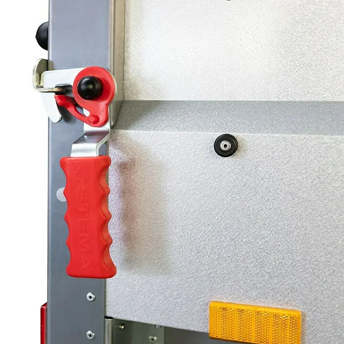 Stema Anhänger BASIC STL 1000-21-13 - Nutzlast: 781 kg, Einachser, Kasteninnenmaß: 210 x 128 x 35 cm, Gebremst - Nahaufnahme eines rot-silbernen Anhängers mit einem stabilen roten Griff und einem gelben Reflektor.