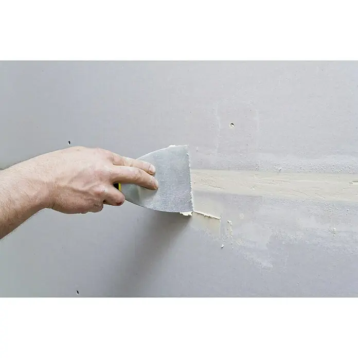 Knauf Feinspachtel Uniflott Finish - 20 kg, Gebrauchsfertig - Handwerker verwendet Spachtelmasse, um eine beschädigte Trockenbauwand zu reparieren. Der Spachtel wird zum Glätten der Masse verwendet.