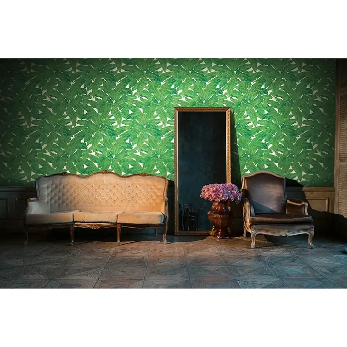 A.S. Création Metropolitan Stories Vliestapete Blätter - Grün/Braun, Floral, 10,05 x 0,53 m - Ein elegantes Interieur mit einem Sofa, einem Sessel und einem Spiegel, dekoriert mit einer grünen Blättertapete, die einen luxuriösen und stilvollen Raum schafft.