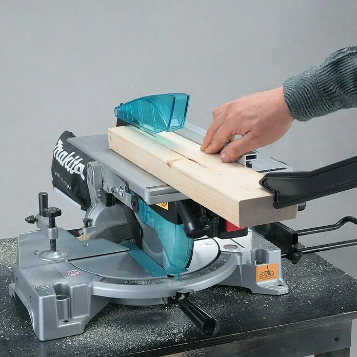 Makita Kapp- & Gehrungssäge LH1040F - 1.650 W, Durchmesser Sägeblatt: 260 mm, Leerlaufdrehzahl: 0 U/min - 4.800 U/min - Eine Makita-Kapp- und Gehrungssäge im Einsatz, die ein Holzbrett schneidet. Präzision und Leistung in einem Werkzeug für Profis und Heimwerker.