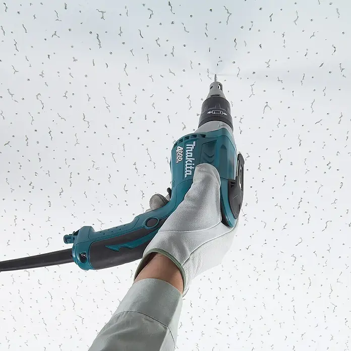 Makita Atornillador para placas de yeso FS4200 - 570 W, 4.000 r.p.m. - Se está atornillando un destornillador Makita 4000 en un techo, sostenido por una mano que lleva un guante blanco.