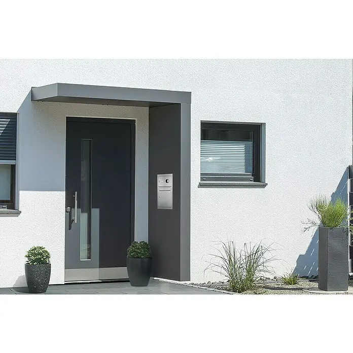Gutta Rechteckvordach Gutta BS Plus 200 UP ST BK Audio - 200 x 90 x 15,5 cm, Seitenteil rechts, Briefkastenanlage Edelstahl mit Audio-Funktion - Moderne Haustür mit Briefkasten in stilvollem Design, umgeben von dekorativen Pflanzen, die das Gesamtbild des Eingangsbereichs aufwerten.