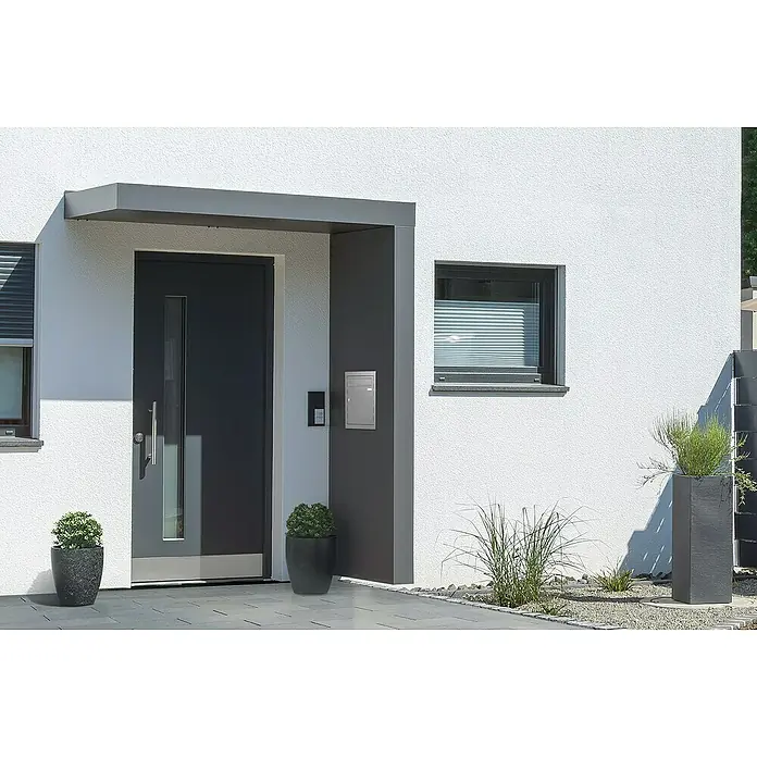Gutta Rechteckvordach BS Plus 200 UP ST BK - 200 x 90 x 15,5 cm, Seitenteil rechts, Briefkasten Edelstahl - Eine moderne Haustür mit dunkelgrauem Rahmen und Glaseinsatz unter einem Vordach, flankiert von Pflanzenkübeln.