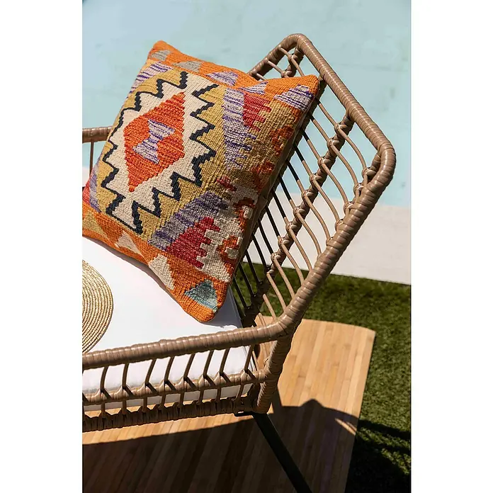 Conjunto de muebles Delfina - 3 pzs., Ratán sintético/Acero, Marrón - Cojín decorativo kilim sobre una silla de ratán, que añade un toque elegante a la zona exterior con su diseño étnico.