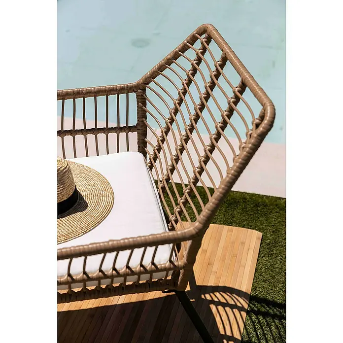 Conjunto de muebles Delfina - 3 pzs., Ratán sintético/Acero, Marrón - Primer plano de una butaca de mimbre con cojín blanco y sombrero, ideal para exterior.