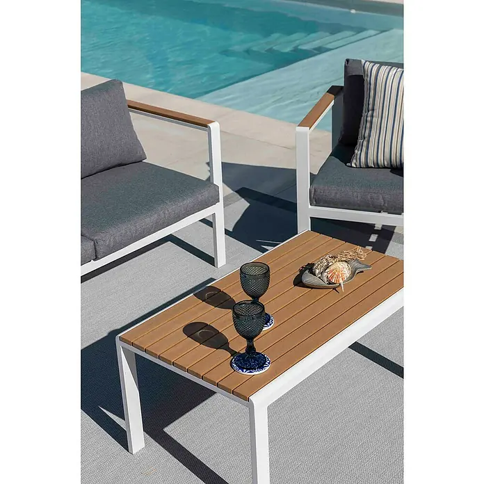 Sunfun Conjunto de muebles Selma - 4 pzs., Aluminio/Polywood, Blanco - Primer plano de una mesa de centro moderna con bebidas y decoración, rodeada de elegantes muebles de exterior junto a una piscina.