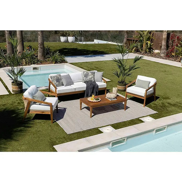 Sunfun Conjunto de muebles Anna - 4 pzs., Madera de acacia, Marrón - Un elegante conjunto de salón para exteriores con marcos de madera, cojines blancos y una mesa de centro a juego sobre una alfombra elegante.