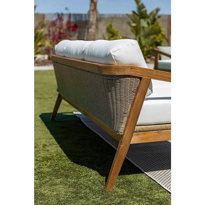 Sunfun Conjunto de muebles Anna - 4 pzs., Madera de acacia, Marrón - Primer plano de un sofá de jardín con estructura de madera y cojines blancos sobre césped verde, que ofrece comodidad y estilo para exteriores.