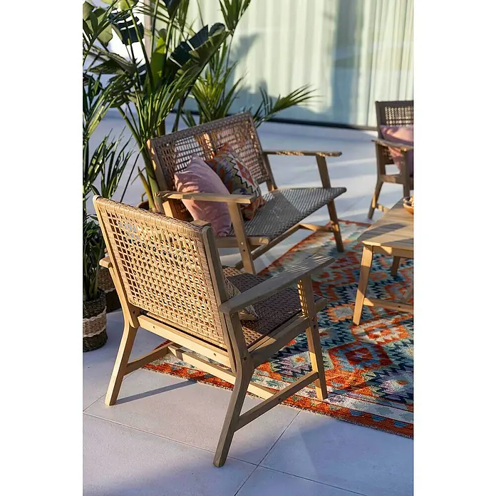 Conjunto de muebles Violeta - 4 pzs., Madera de acacia/Ratán sintético, Marrón - Acogedora escena exterior con sillas de mimbre y una alfombra colorida, ideal para relajarse al aire libre.