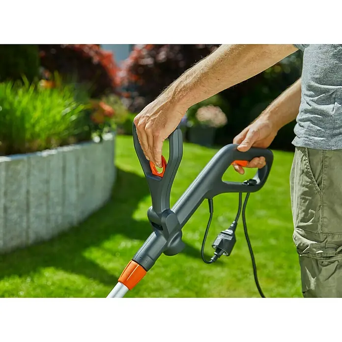 Gardena Elektro-Rasentrimmer ComfortCut 550/28 - 550 W, Schnittbreite Faden: 28 cm - Nahaufnahme eines Gardena-Rasentrimmers in Aktion, der von einer Person im Garten bedient wird.