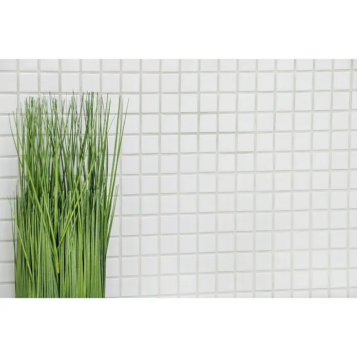 Mosaikfliese Quadrat Uni B 100 - 32,6 x 30 cm, Weiß, Glänzend - Nahaufnahme einer weißen Mosaikfliese mit einem Grasbüschel, die ein Gefühl von Reinheit und natürlicher Eleganz vermittelt.