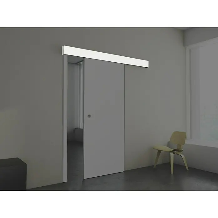 Solid Elements Embellecedor exterior Blanco Lacado - 2.000 x 100 mm - Imagen de una puerta corredera gris en una habitación moderna, con una silla de madera clara en la esquina. La puerta está parcialmente abierta.
