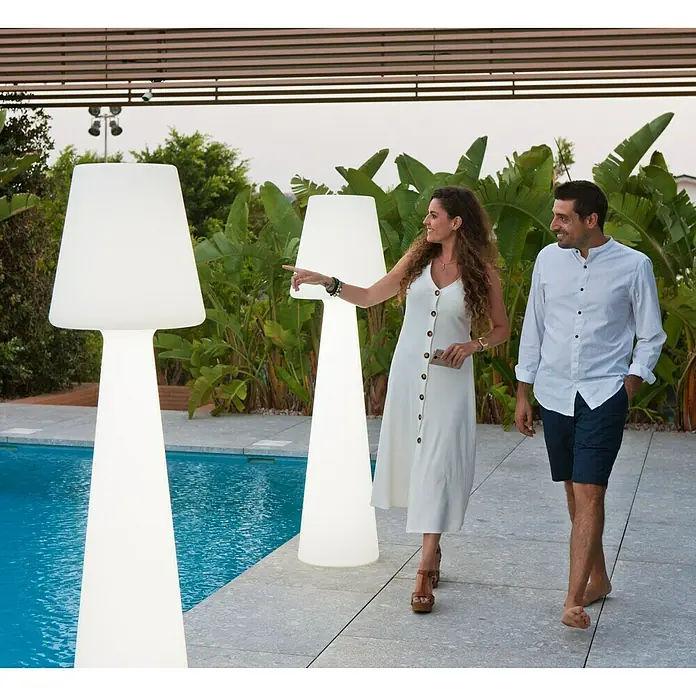 New Garden Lámpara de diseño para exterior LED Lola - 8 W, Blanco frío, Altura: 165 cm - Una pareja pasea junto a una piscina iluminada por grandes lámparas de pie. Las lámparas proporcionan una luz agradable.