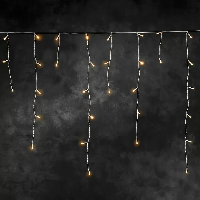 Konstsmide LED-Lichtervorhang Eisregen - Außen, 0,75 m, Bernstein, 200 Stk., Netzbetrieben - Weiße Lichterkette mit warmweißen Glühbirnen vor dunklem, strukturiertem Hintergrund.