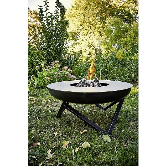 Buschbeck Grillplatte Plancha - Passend für: Feuerschale mit Ø 60 cm - Feuerstelle im Freien mit modernem Design. Sie steht auf einem Rasen umgeben von viel Grün und lädt zum Verweilen ein.