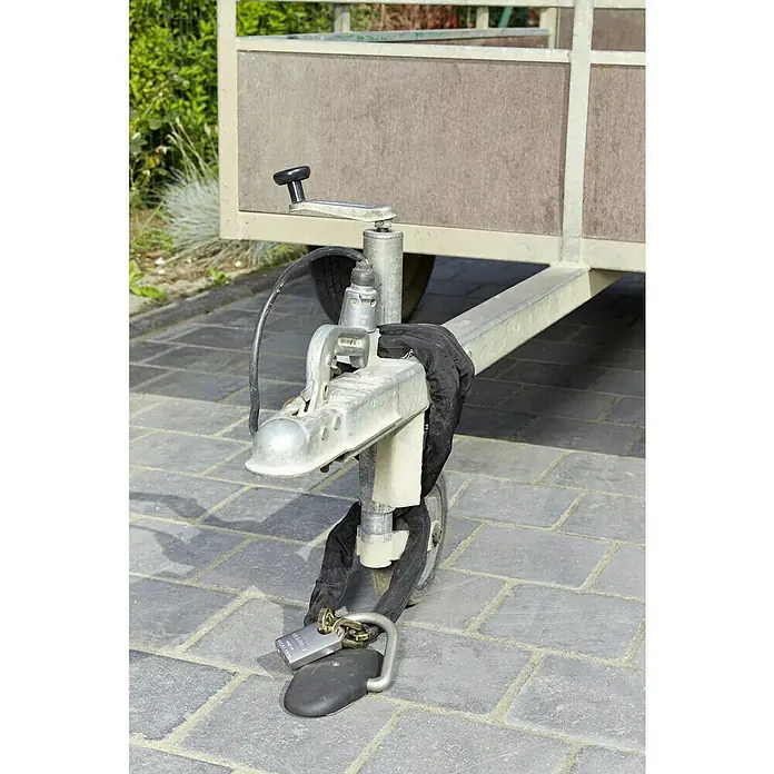 Mottez Verankerungshalter A080Q - Geeignet für: Fahrräder - Ein Anhänger mit einer robusten Kupplung, gesichert durch ein stabiles Kettenschloss und ein Vorhängeschloss, steht auf einem gepflasterten Untergrund.