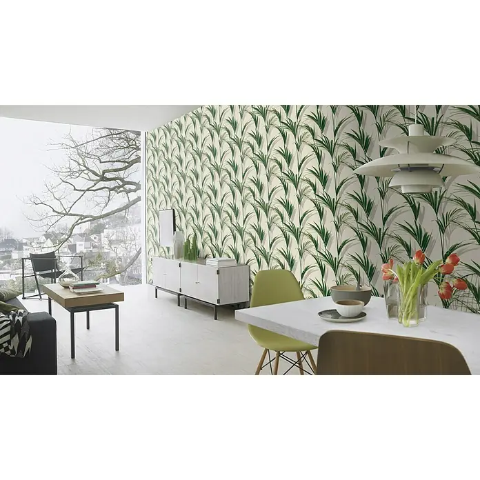 FREUNDIN HOME COLLECTION III Vliestapete Blätter - Weiß/Grün, Floral, 10,05 x 0,53 m - Zimmer mit blattgemusterter Tapete, Esstisch mit Blumen, ein Sofa und ein Schrank unter einem großen Fenster mit Blick auf einen bewölkten Tag.