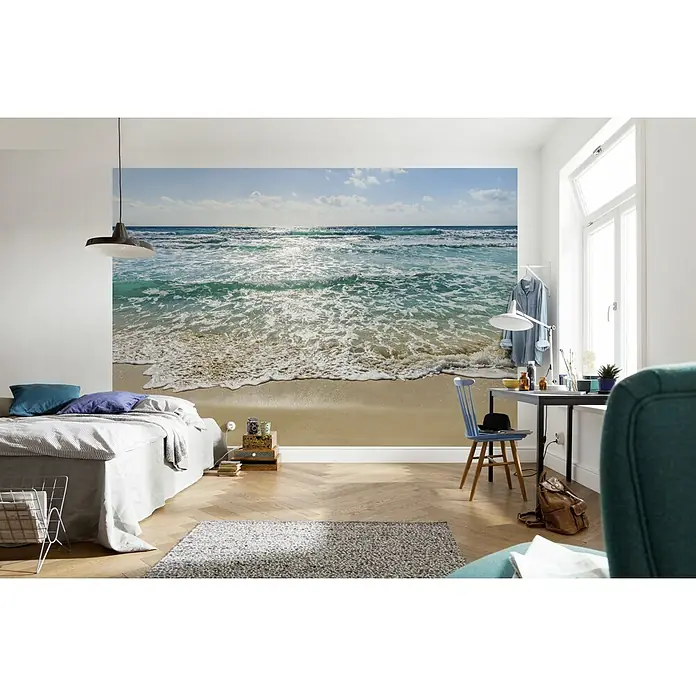 Komar Fototapete Seaside - 8 -tlg., B x H: 368 x 254 cm, Papier - Ein Schlafzimmer mit einer Fototapete von einem Strand und türkisfarbenem Meer, die eine entspannende Atmosphäre schafft. Helle, freundliche Farben dominieren.